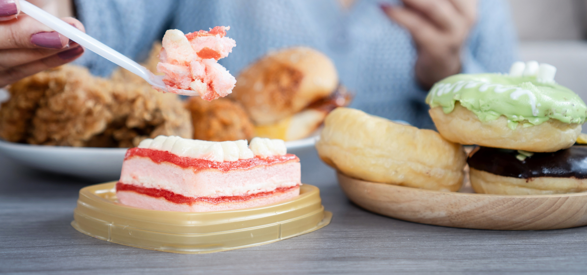 Person eating cake. Lots of different cakes in front of them