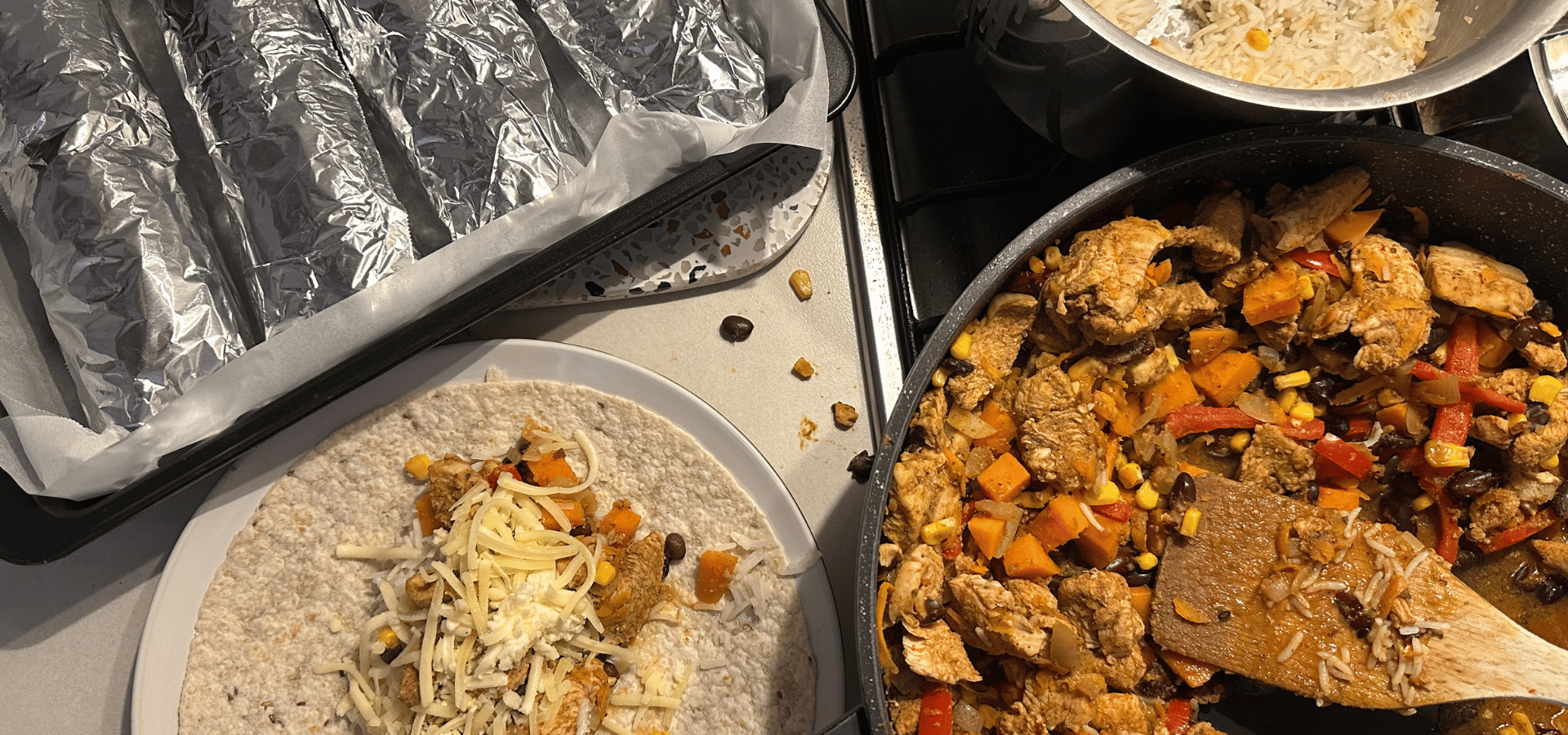 Batch-prepped chicken fajita filling with rice, sweet potato and black beans, portioned into foil-wrapped burritos, an example of low-effort food kept ready to go for ADHD meal prep.