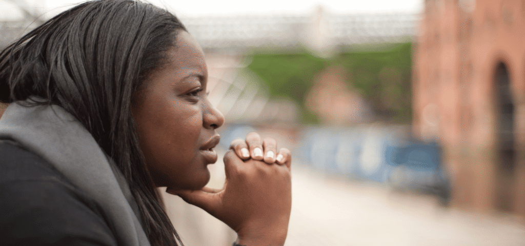 Woman resting her chin on her hands, looking out thoughtfully