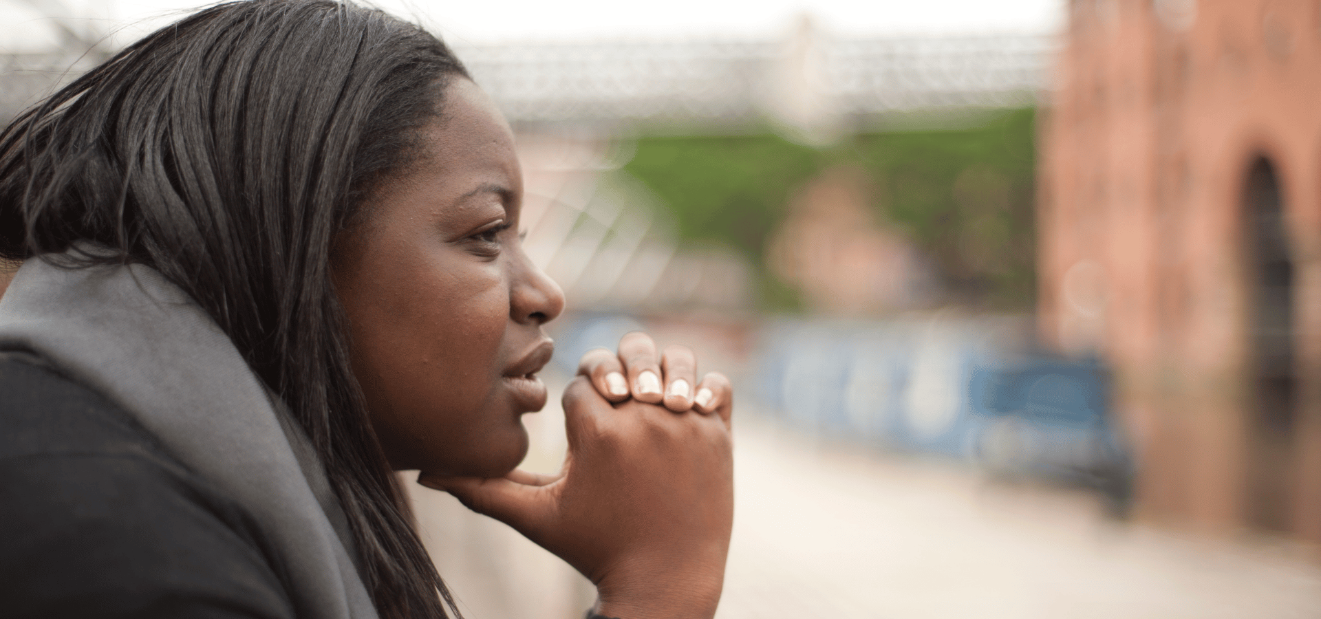 Woman resting her chin on her hands, looking out thoughtfully